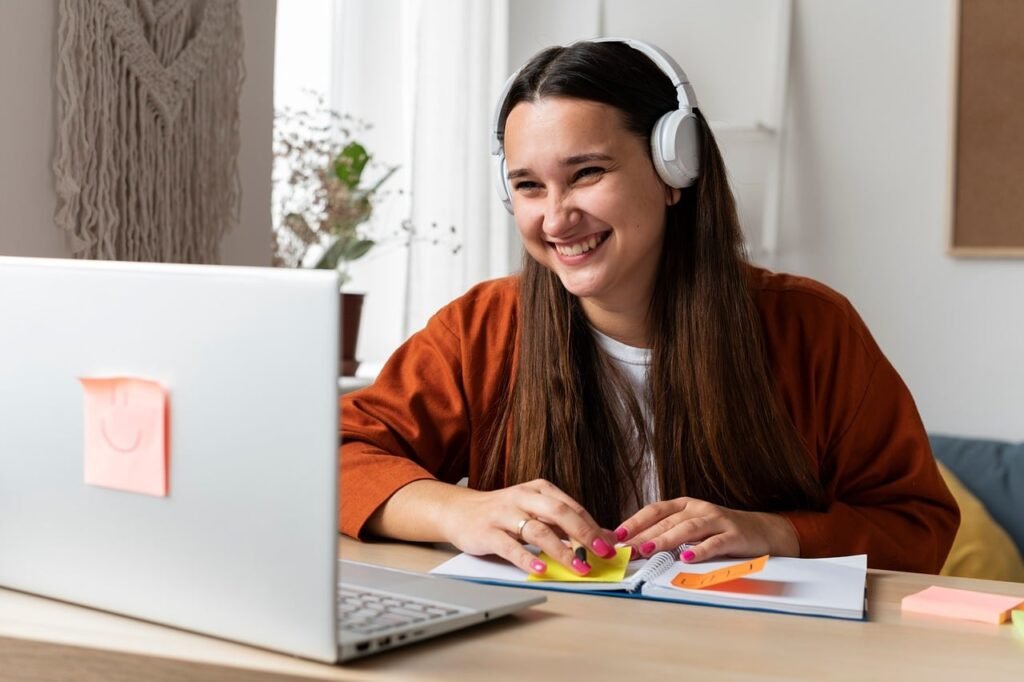 Mujer sonriente trabajando con su portátil y una libreta con notas adhesivas en su escritorio