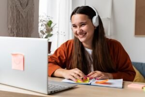 Mujer sonriente trabajando con su portátil y una libreta con notas adhesivas en su escritorio