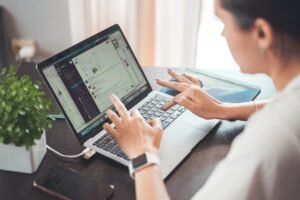 Mujer trabajando en su portátil desde una mesa de casa, revisando el correo de su negocio